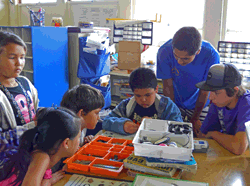 High school robotics students work with a First Lego League team.